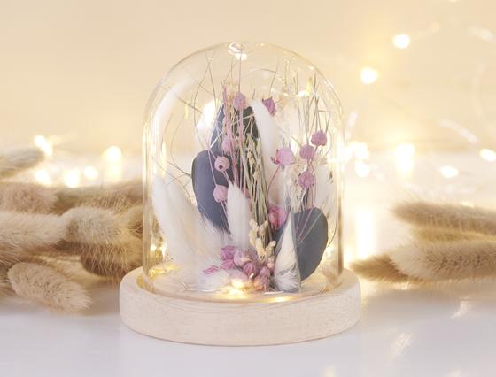 Beleuchtete Glasglocke mit Trockenblumen